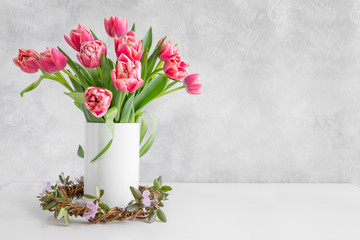Bouquet of red tulip in vase on white vintage table.