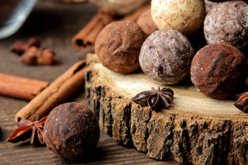 assorted chocolates. candy balls of different types of chocolate on a brown wooden table. cinnamon and cocoa