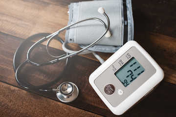 Stethoscope and Sphygmomanometer an electronic blood pressure monitor on a wooden table. concept of health and medical