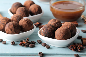 assorted chocolates. candy balls of different types of chocolate on a blue wooden table. cocoa, cinnamon, star anise and coffee beans.