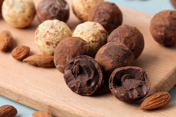 assorted chocolates. Candy balls of different types of chocolate on a wooden board on a blue wooden table. almond