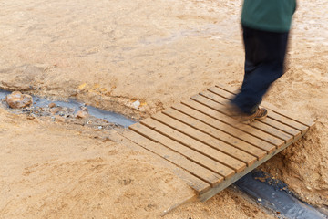 Mensch l&auml;uft &uuml;ber eine kleine Holzbr&uuml;cke im Geothermalgebiet Hverir, Island