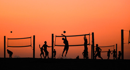 Volleyball players in silhouette at sundown in California