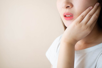 Young woman suffering from toothache over white background. Cause of tooth pain include tooth...