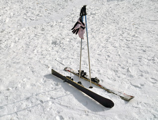 Children's alpine skis, ski poles and gloves lie on the snow