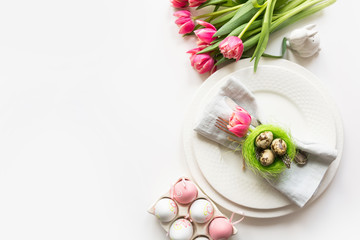 Easter table setting with pink tulip on white. Spring romantic dinner. Top view and space for your text.