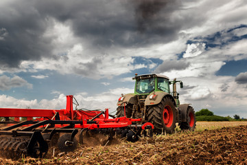Obraz premium Tractor preparing land for sowing out in the field
