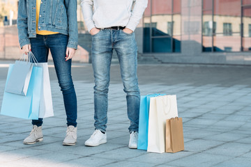 Casual shopping couple. Sale consumerism. Man and woman with paper bags. Legs in jeans.