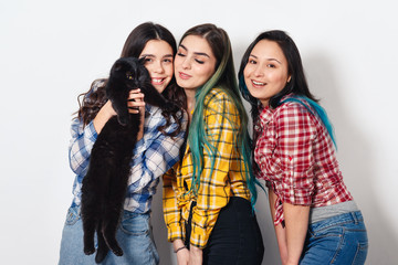 portrait of three young beautiful girls with a cat in her arms on white light background