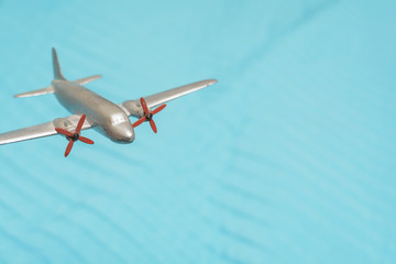 Toy plane flys high above for travel and transport concept with blue sky