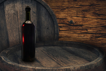Red wine bottle on a old barrel table background wood wall.
