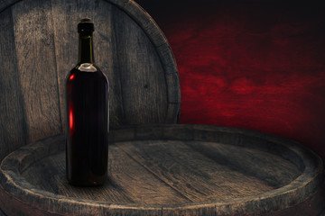 Red wine bottle on a old barrel table background wood wall.