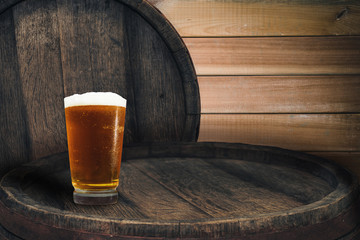 Wooden barrel and glass of beer on a barrel table of wood.