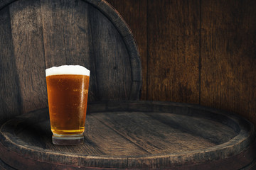 Wooden barrel and glass of beer on a barrel table of wood.