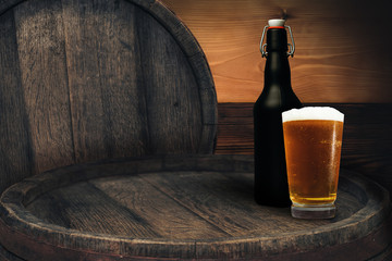 Wooden barrel and glass of beer on a old oak table of wood.