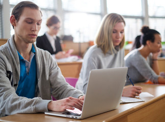 Man with laptop among students in an auditorium
