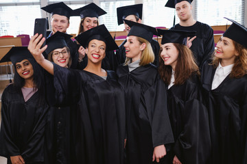 Multi ethnic group of graduated students taking selfie