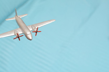 Toy plane flys high above for travel and transport concept with blue sky
