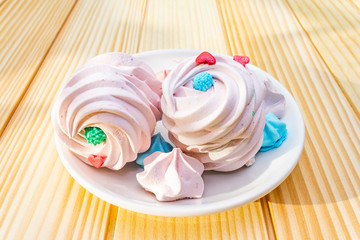 Romantic sweet breakfast concept. Meringue (cake) on plate. On wooden background, close up.