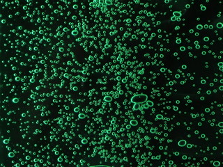 Close - up of air bubbles of different colors, in water isolated on dark background