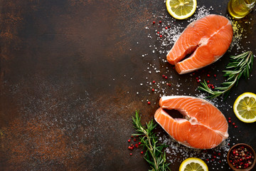 Raw salmon steaks marinated with lemon, rosemary, spices and olive oil.Top view with copy space.