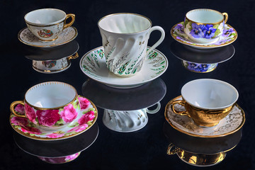On a black background antique coffee cups and cups of modern design.