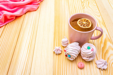 Romantic sweet breakfast concept. Green tea, lemon, meringue (cake). On wooden background with pink cloth.