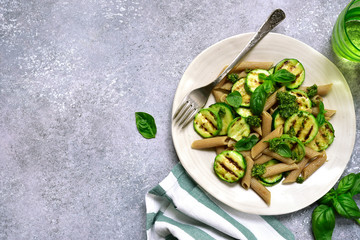 Whole grain spring penne pasta with grilled zucchini and basil pesto.Top view with copy space.