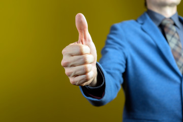 Business man hand with thumb up. Yellow backgraund.