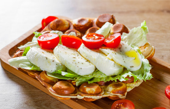 Hong Kong bubble waffles sandwich with Mozzarella cheese and vegetables on wooden table background