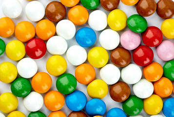 colorful candy on white background. Rainbow sprinkles for topping ice cream and cake. Small candies in colored chocolate glaze.