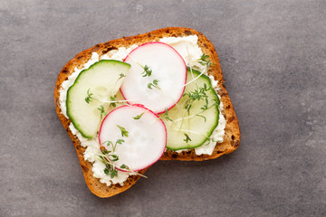 Sandwich with cereals bread and salami on dark marble background.