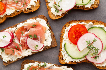 Sandwich with cereals bread and salami on dark marble background.