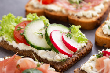 Sandwich with cereals bread and salami on dark marble background.