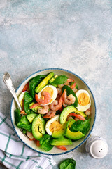 Avocado salad with baby spinach, shrimps and boiled eggs.Top view with copy space.