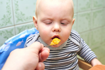 Parent feeds baby a pumpkin with a spoon