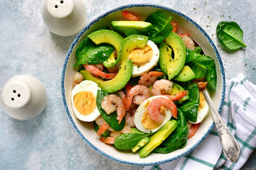 Avocado salad with baby spinach, shrimps and boiled eggs.Top view with copy space.