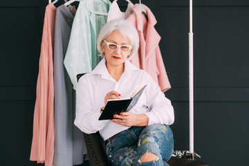 Personal fashion stylist. Successful business. Confident senior lady making notes in day planner.