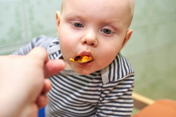 Parent feeds baby a pumpkin with a spoon