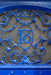 House number 18 with the eighteen worked in metal in a decorative metal grating in front of a glass pane