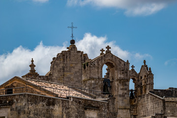 Fototapeta na wymiar Summer blue sky and church roof with religious crosses, view of ancient town of Matera, the Sassi di Matera, Basilicata, Southern Italy, cloudy summer August day