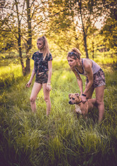 Naklejka na ściany i meble Girls playing around in nature and dogs