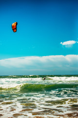 Silhouette of windsurfer racing breaking wave