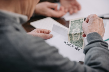 cropped view of man holding envelope with 'roth ira' lettering and dollar banknote