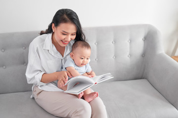 Young asian mother reading book to baby. Sweet moment. - Powered by Adobe