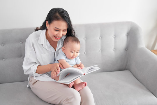 Young asian mother reading book to baby. Sweet moment.