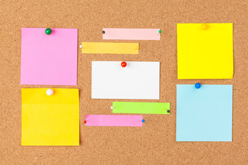 Cork board with several colorful blank notes with pins