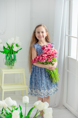 Portrait of a beautiful blue-eyed girl, a little girl among spring flowers in a bright room.