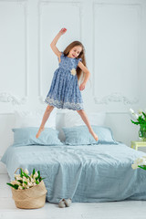 Portrait of a beautiful blue-eyed girl, a little girl among spring flowers in a bright room.