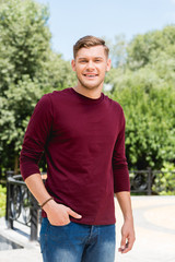 happy young man smiling while standing with hand in pocket